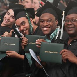 students smiling and holding their diploma covers